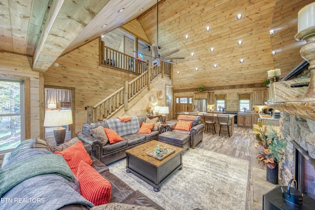 living area featuring a fireplace, stairway, light wood-style floors, wooden walls, and wooden ceiling