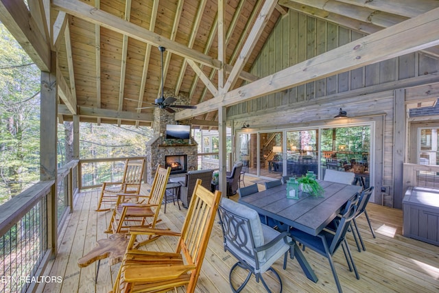 wooden deck with a ceiling fan, an outdoor stone fireplace, and outdoor dining area