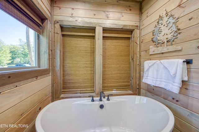 bathroom featuring wooden walls and a freestanding bath