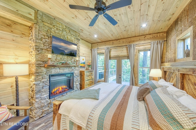 bedroom with wooden walls, wooden ceiling, wood finished floors, access to outside, and a fireplace