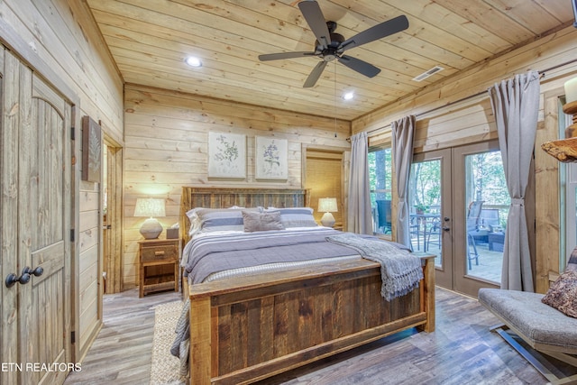 bedroom featuring wooden walls, wood ceiling, light wood-style floors, access to exterior, and french doors