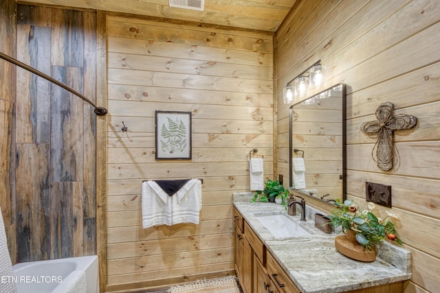 bathroom featuring a tub, wood walls, vanity, and walk in shower