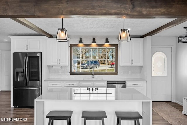 kitchen featuring stainless steel appliances, a breakfast bar, a sink, beam ceiling, and dark wood-style floors