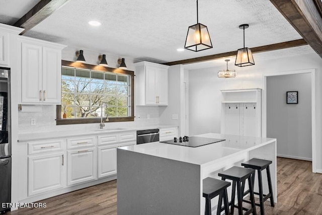 kitchen featuring black electric stovetop, stainless steel dishwasher, a sink, wood finished floors, and beamed ceiling