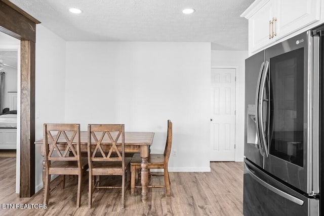 dining room featuring light wood-type flooring, a textured ceiling, baseboards, and recessed lighting