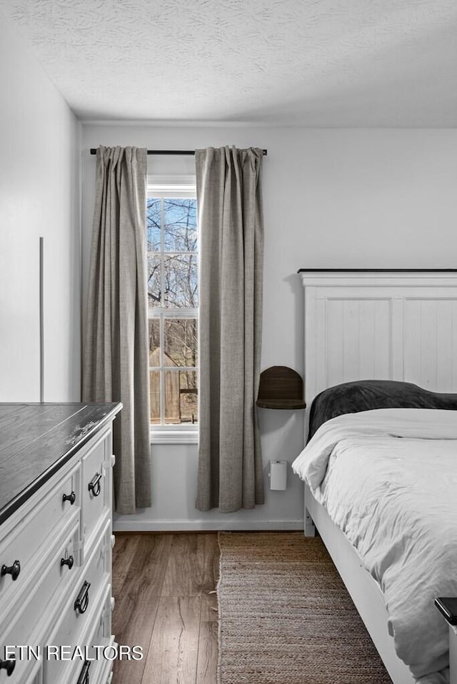 bedroom with a textured ceiling and wood finished floors