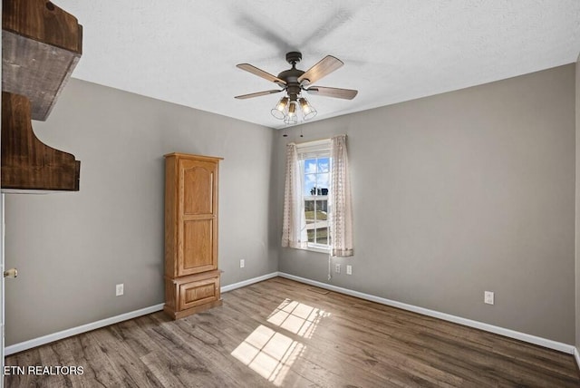 unfurnished room featuring a ceiling fan, baseboards, and wood finished floors