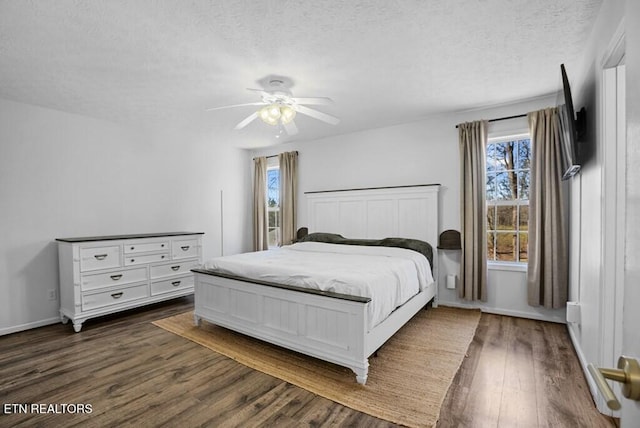 bedroom featuring ceiling fan, a textured ceiling, baseboards, and dark wood-type flooring