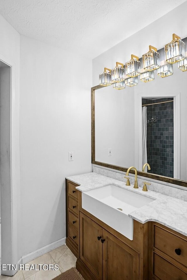 full bath featuring a textured ceiling, vanity, a shower with curtain, baseboards, and tile patterned floors