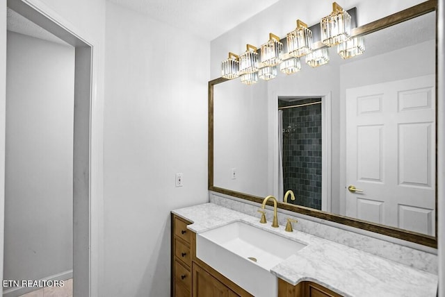 bathroom featuring a chandelier, a tile shower, and vanity