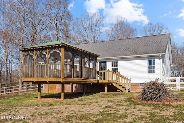 rear view of house featuring a shingled roof, stairway, fence, and a sunroom