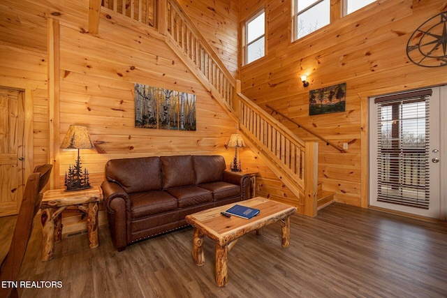 living area with wood walls, stairway, a towering ceiling, and wood finished floors