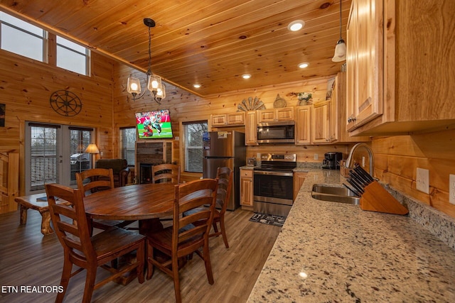 dining space featuring wooden ceiling, light wood-style flooring, an inviting chandelier, wood walls, and a fireplace