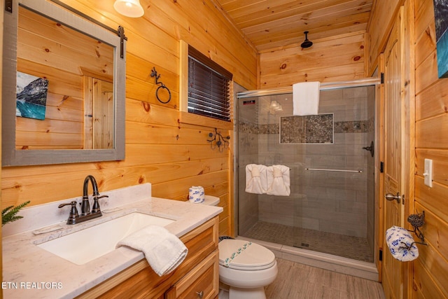 bathroom featuring wooden walls, toilet, a shower stall, and vanity