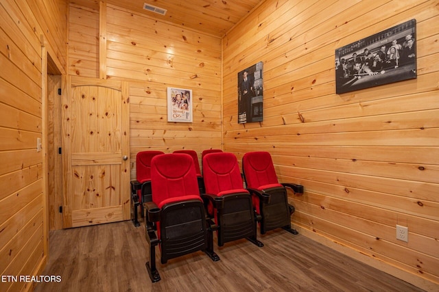 home theater featuring wood walls, visible vents, and wood finished floors