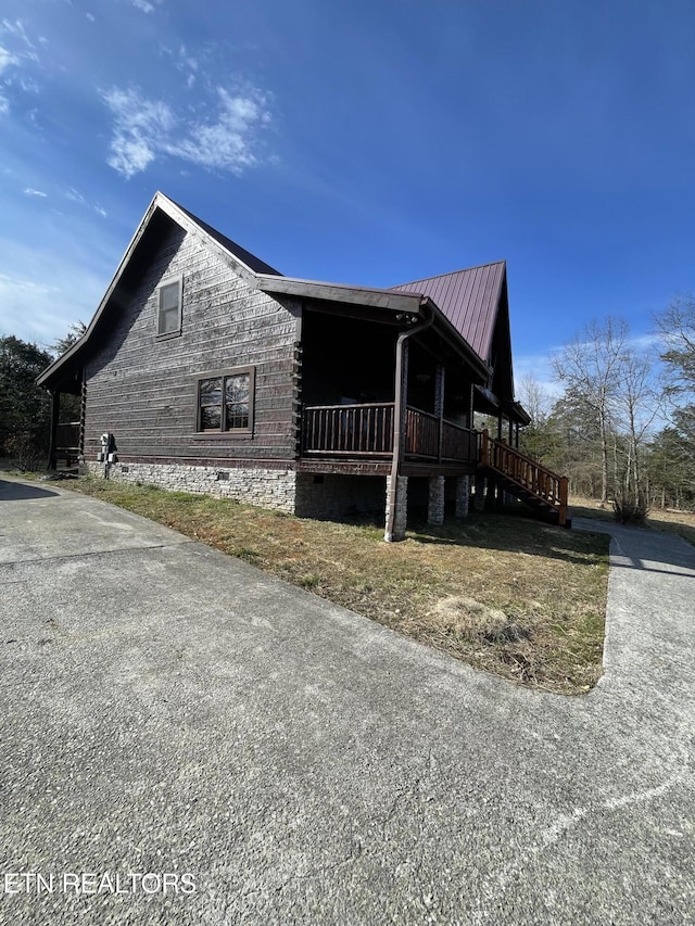 view of side of property with crawl space, a porch, and metal roof