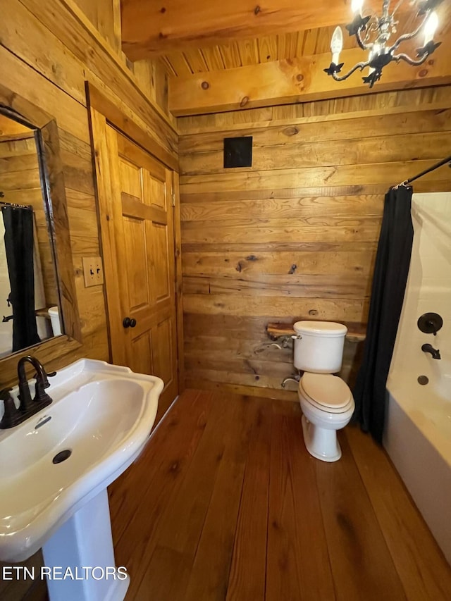 full bathroom with toilet, a sink, wood walls, beamed ceiling, and hardwood / wood-style flooring