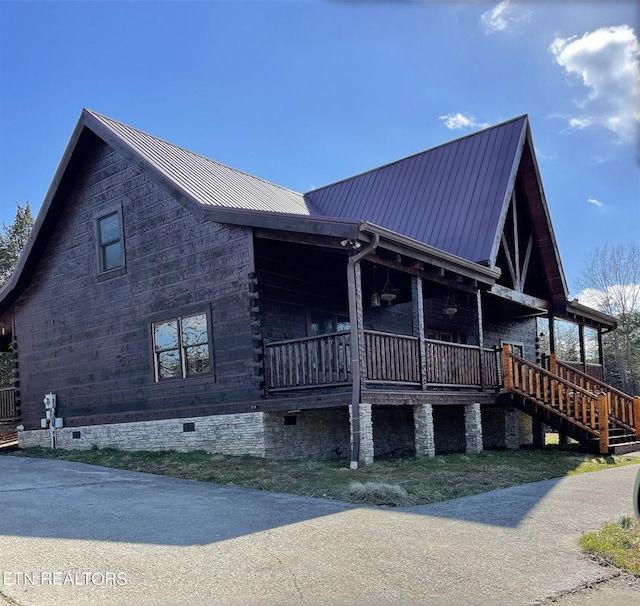 view of home's exterior with crawl space, covered porch, and metal roof