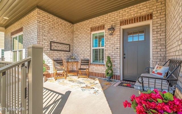 property entrance featuring covered porch and brick siding