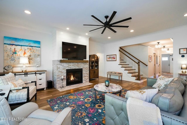 living area with recessed lighting, a fireplace, wood finished floors, a ceiling fan, and stairs