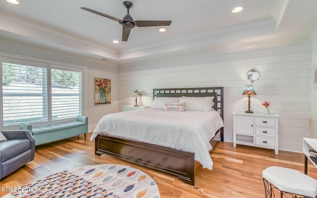 bedroom with light wood finished floors, a tray ceiling, and recessed lighting