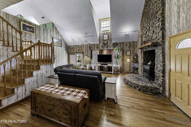 living room with a textured ceiling, wood finished floors, stairway, plenty of natural light, and wallpapered walls