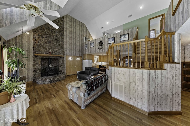 living room with high vaulted ceiling, a wood stove, ceiling fan, and wood finished floors