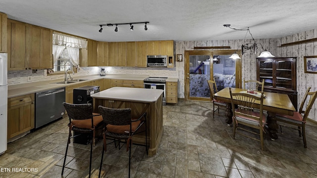 kitchen with appliances with stainless steel finishes, a center island, light countertops, and a sink