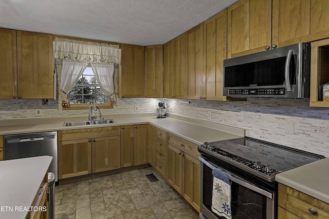 kitchen with tasteful backsplash, light countertops, visible vents, appliances with stainless steel finishes, and a sink