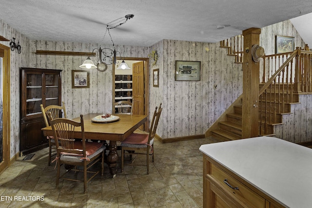 dining space featuring wallpapered walls, stairs, baseboards, and a textured ceiling