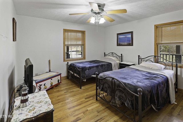 bedroom with a ceiling fan, light wood-style flooring, and a textured ceiling