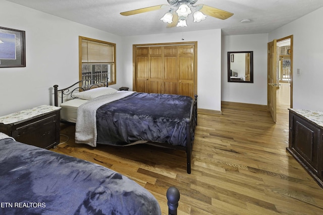 bedroom with ceiling fan, a closet, wood finished floors, and baseboards