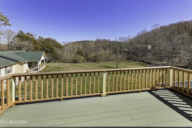 wooden terrace featuring a yard and a view of trees