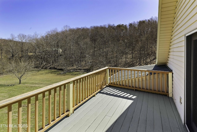 wooden terrace with a yard and a forest view