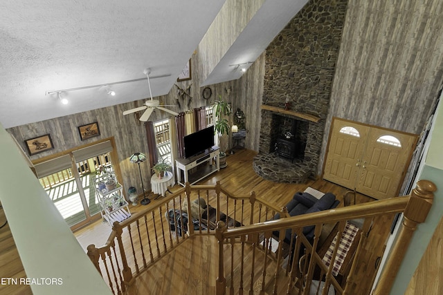 living area with wooden walls, a textured ceiling, and wood finished floors