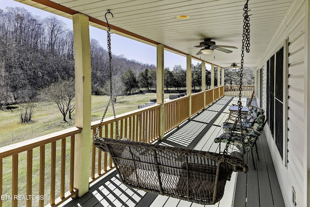 wooden deck featuring a yard, covered porch, and ceiling fan