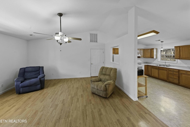 sitting room featuring light wood-type flooring, baseboards, visible vents, and vaulted ceiling