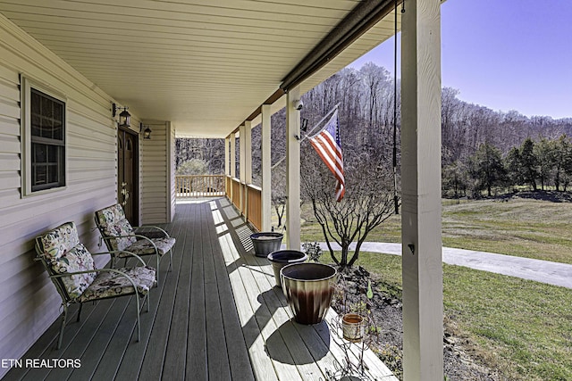 wooden deck featuring covered porch and a yard