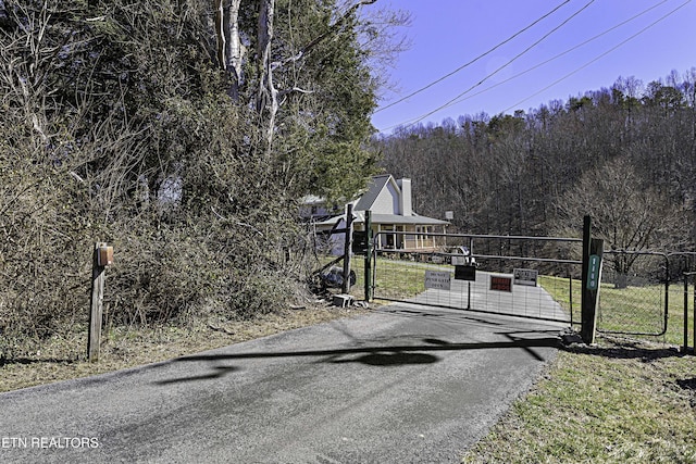 view of street featuring a gate and a wooded view