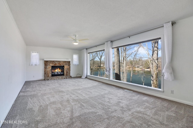 unfurnished living room with carpet floors, a textured ceiling, and a stone fireplace