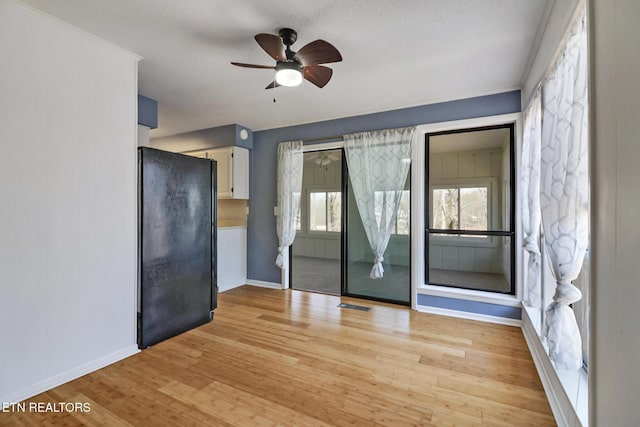 empty room featuring baseboards, a ceiling fan, and light wood-style floors