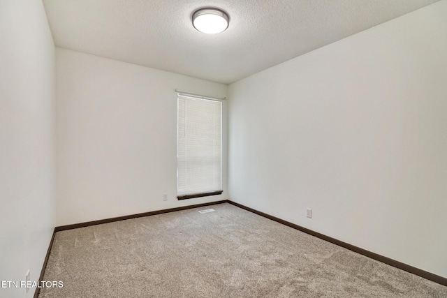 carpeted empty room featuring visible vents, a textured ceiling, and baseboards