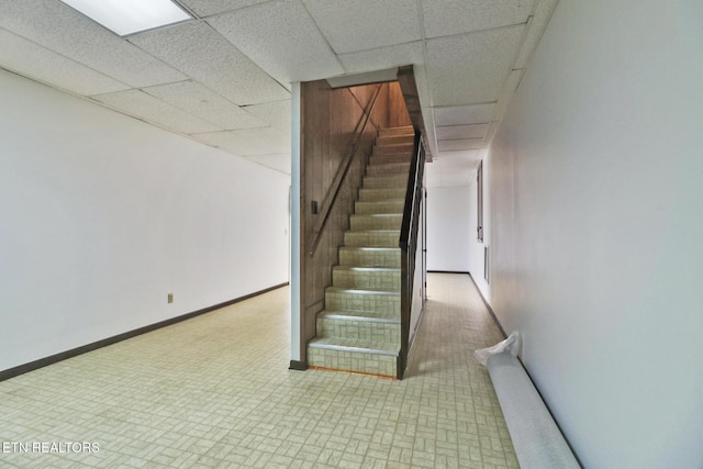 staircase featuring a drop ceiling and baseboards