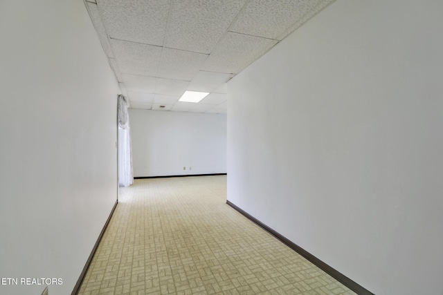 hall featuring a drop ceiling and baseboards