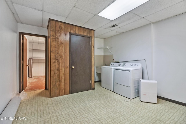 washroom featuring visible vents, washing machine and dryer, wooden walls, laundry area, and baseboards