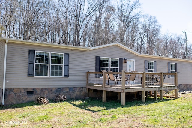 back of property with a deck, crawl space, and a lawn