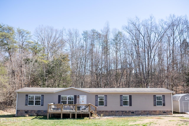 manufactured / mobile home featuring an outbuilding, a storage shed, crawl space, a wooden deck, and a front lawn