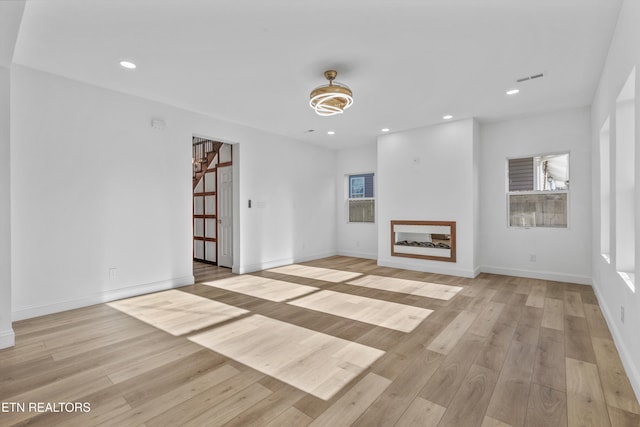 unfurnished living room with stairs, light wood-type flooring, visible vents, and recessed lighting