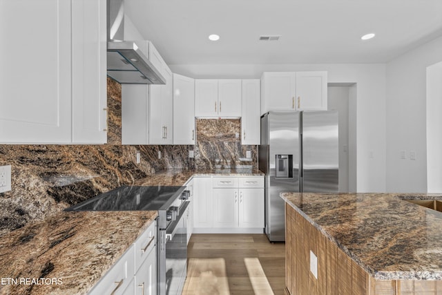 kitchen featuring wall chimney exhaust hood, appliances with stainless steel finishes, light wood-type flooring, white cabinetry, and backsplash