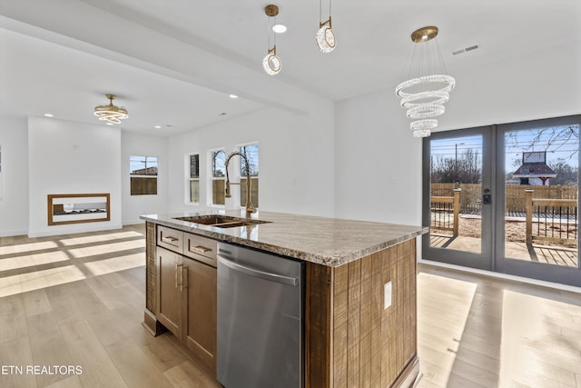 kitchen with light stone counters, visible vents, stainless steel dishwasher, a sink, and light wood-type flooring